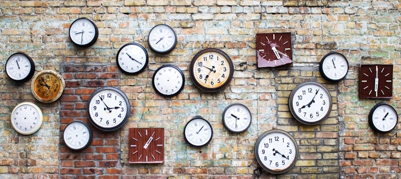 old clocks hanging on a brick wall