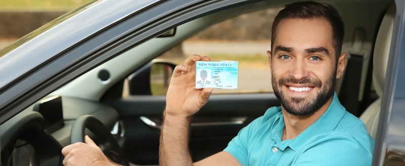 happy driver smiles and shows his license