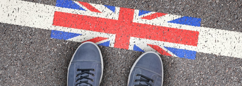 immigrant stares at his shoes looking at UK flag