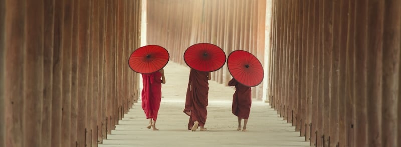 ascetic monks with red umbrellas walk together