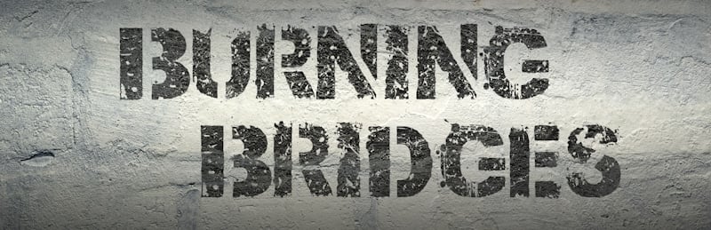 burning bridges sign in white brick wall and gray