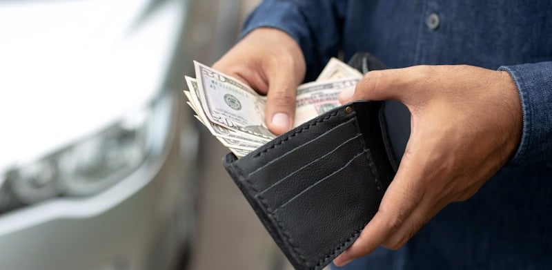 male hands taking money out of wallet to pay