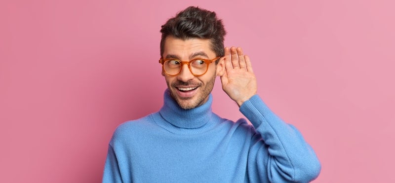 guy in blue sweater and pink background listens out