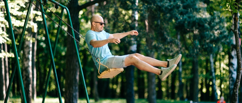 man shows kid like behavior jumps off swings
