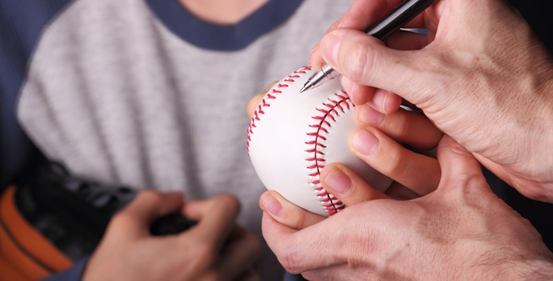 person autographs baseball for kid