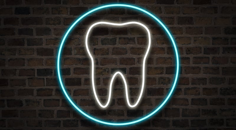 tooth drawn in neon brick wall